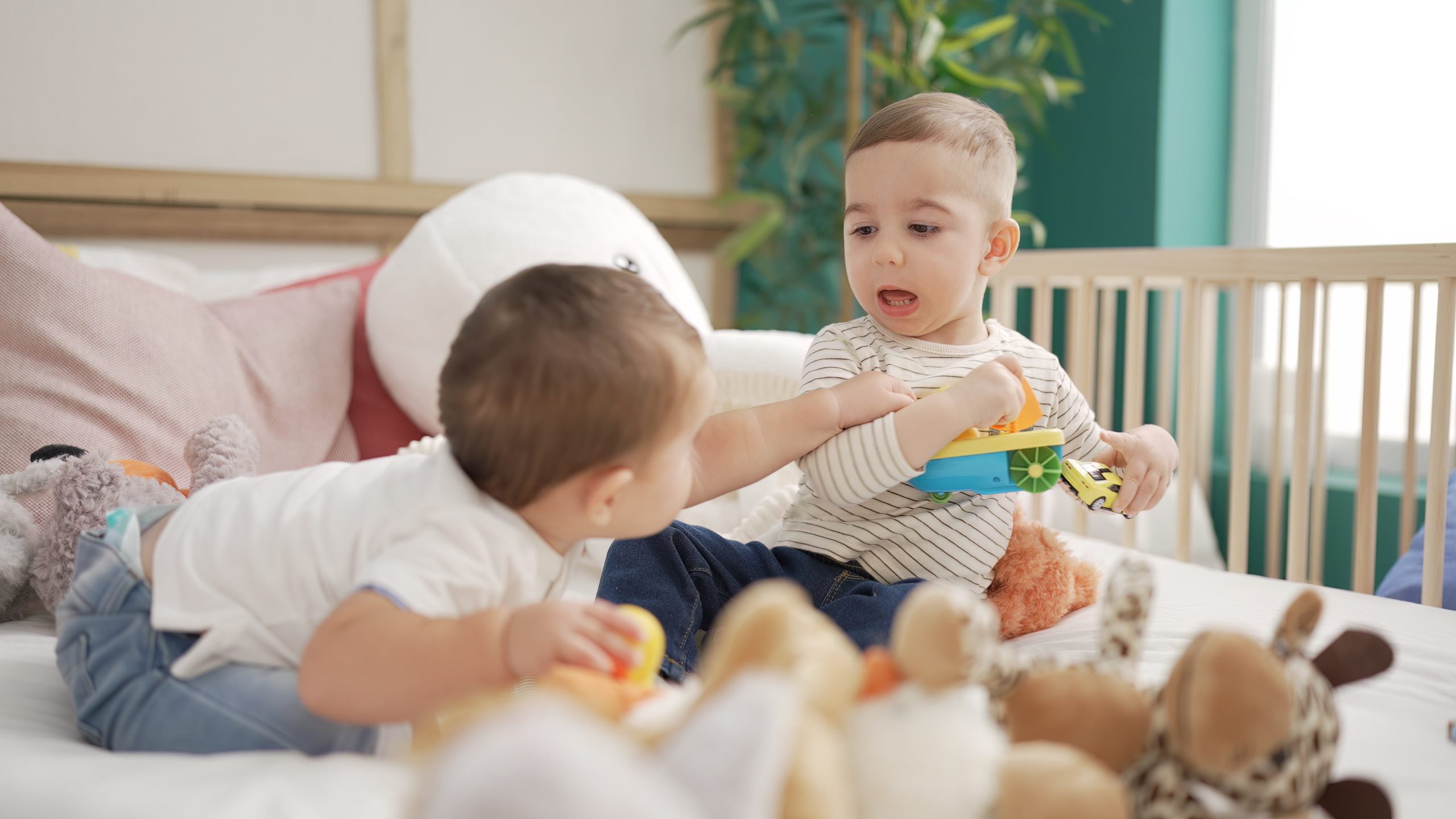Two adorable toddlers sitting on bed playing at kindergarten