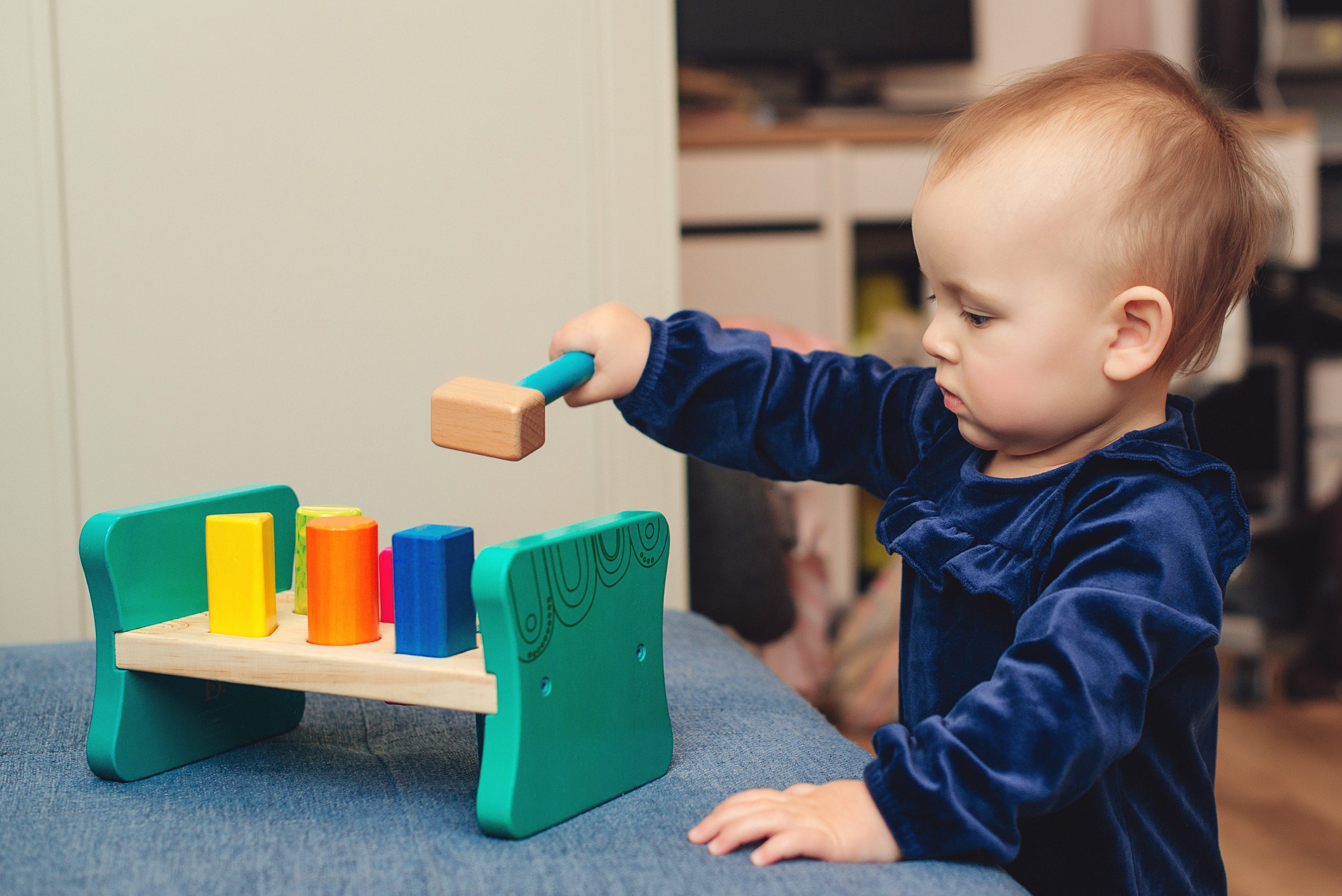 Cute baby girl playing with wooden toys. Toys for small children. Child with an educational toy. Happy childhood concept.